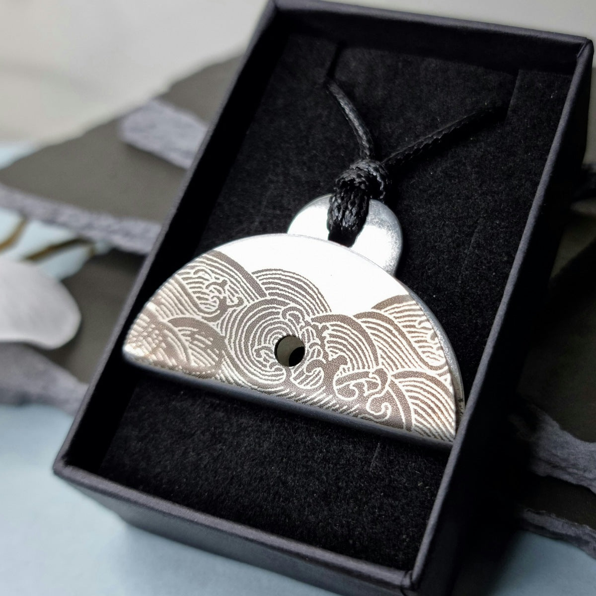 Stainless steel shepherds dog whistle
pendant with decorative engraved wave pattern in a black box
