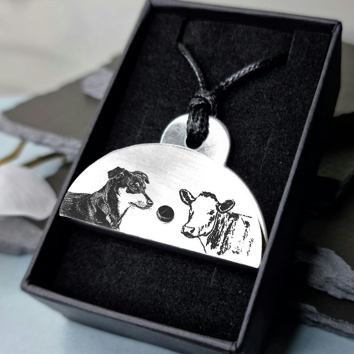 Stainless steel shepherds whistle
necklace featuring engravings of a huntaway and a cow in a black gift box.