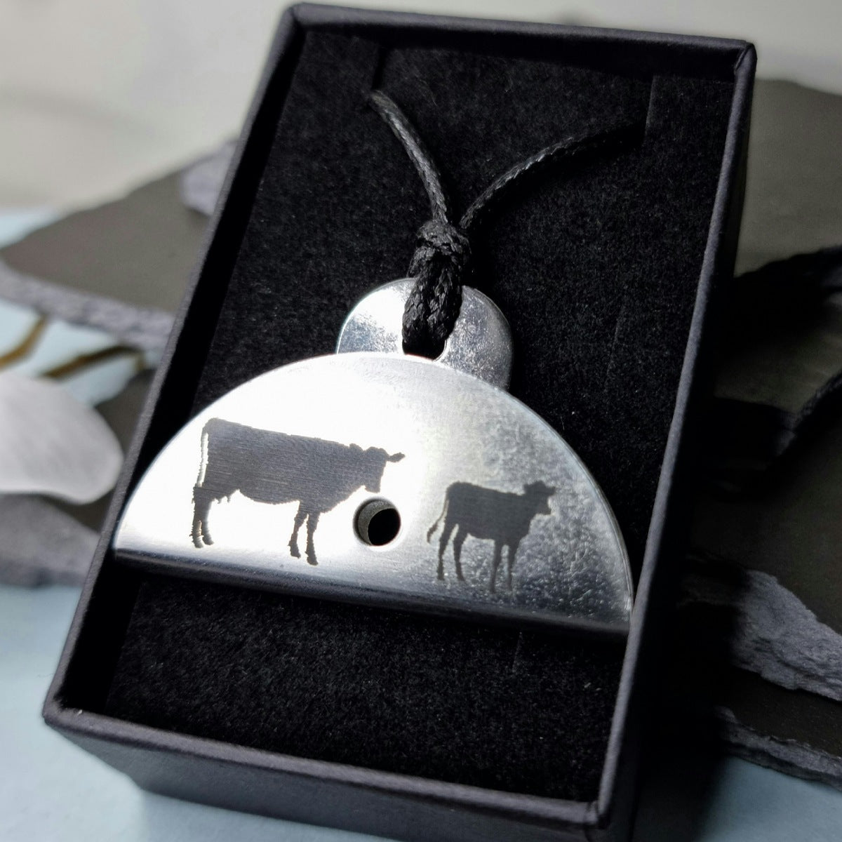 Stainless steel shepherds dog whistle
necklace with cow and calf engraved design in a black box