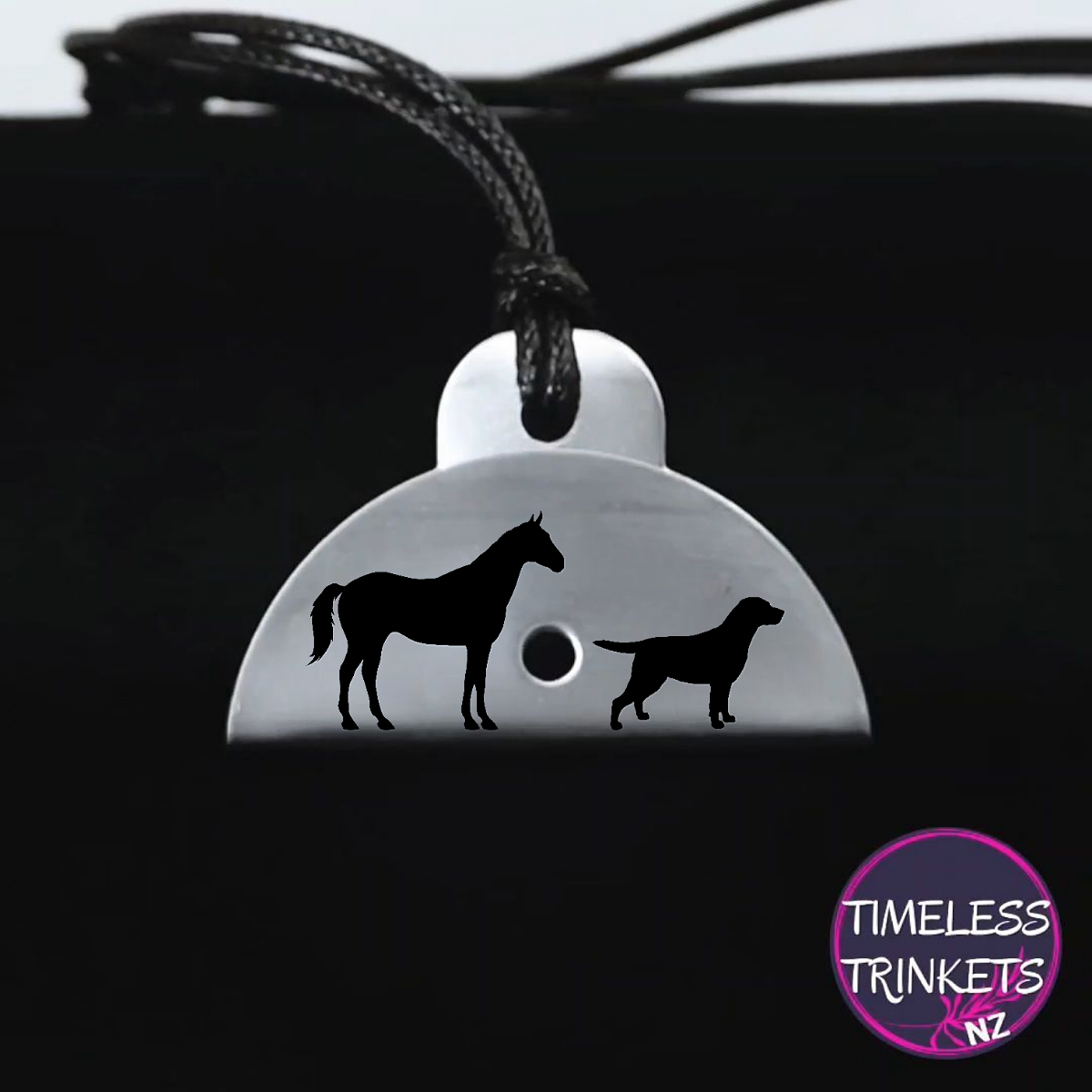 Stainless steel shepherds whistle
pendant with horse and dog silhouettes on a black background, branded 'Timeless Trinkets NZ'.
