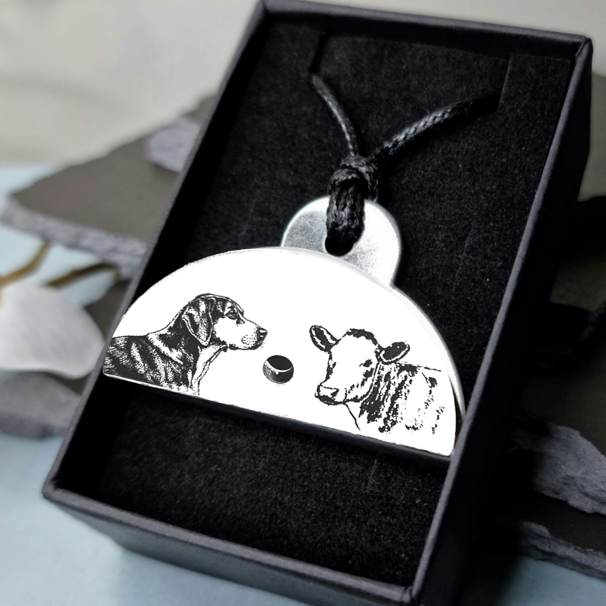 Stainless steel shepherds whistle
pendant with engraved images of a huntaway dog and a cow in a black box.