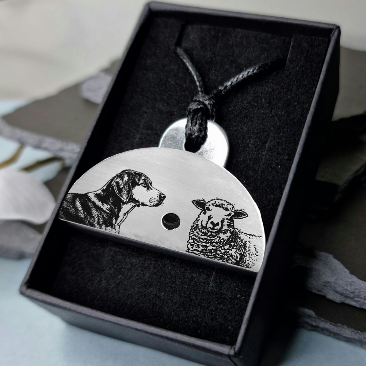 Stainless steel shepherds whistle pendant with engraved images of a huntaway dog and a sheep in a black gift box.