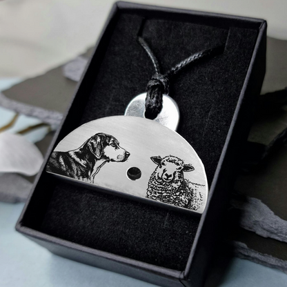 Stainless steel shepherds whistle pendant with engraved images of a huntaway dog and a sheep in a black gift box.